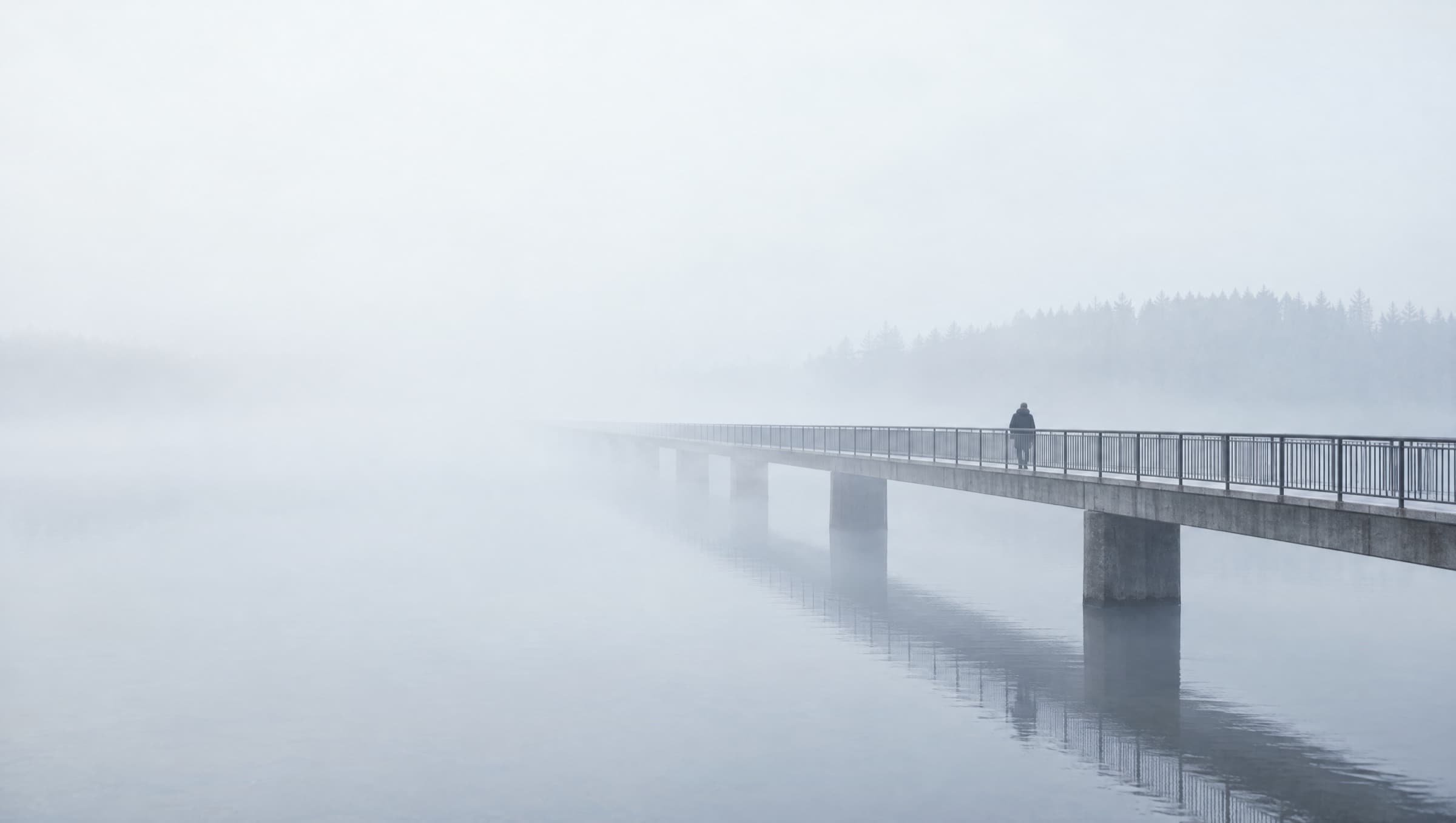 A footbridge crossing a river into fog