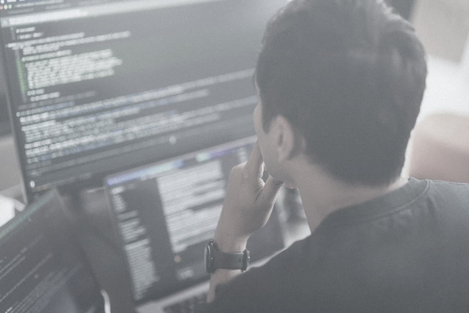 An engineer reviewing code across two screens